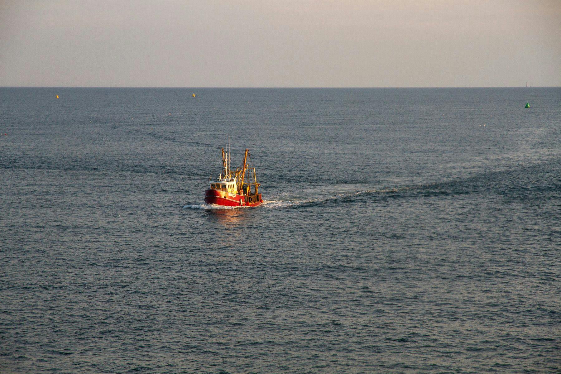 fishing boat returning to port at sunset