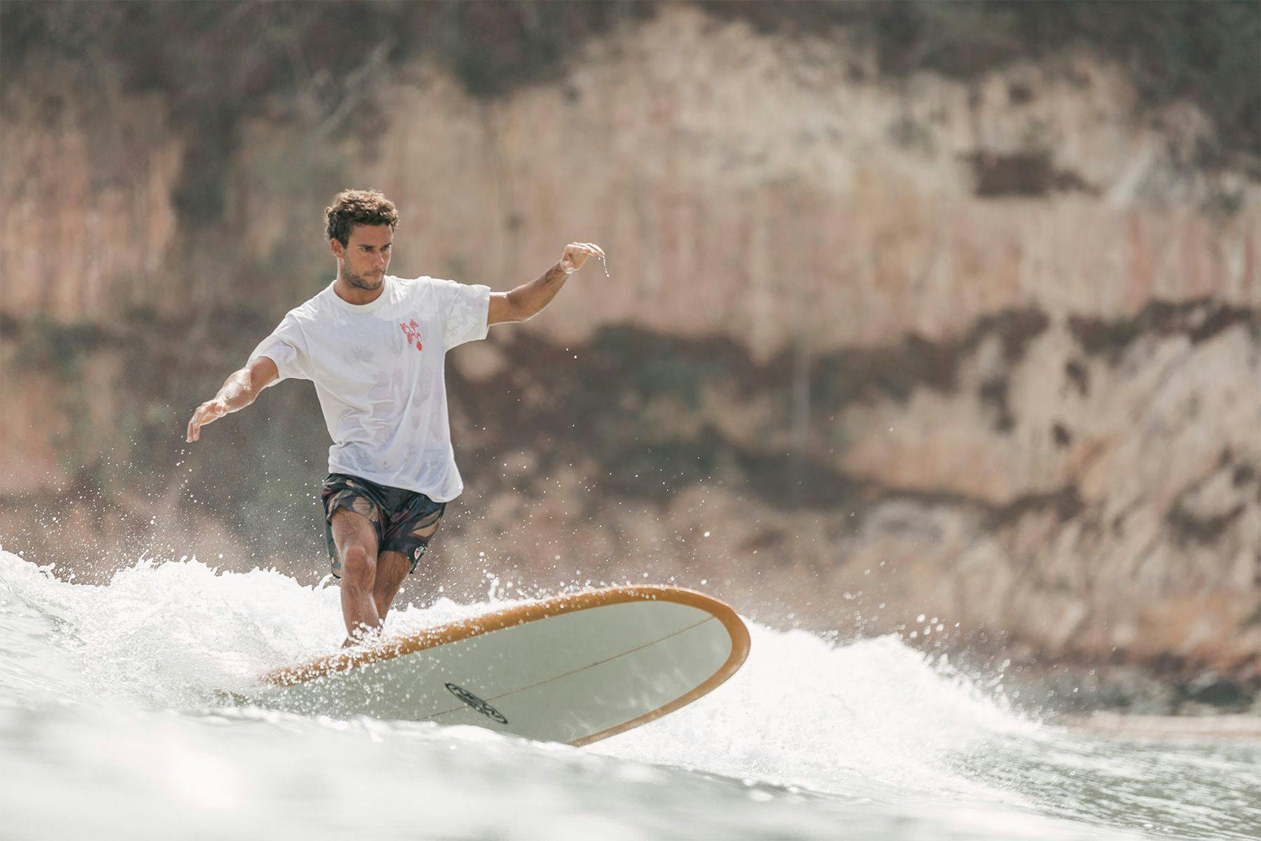 longboard surfer performing a cross-step cutback in brazil, by ana catarina