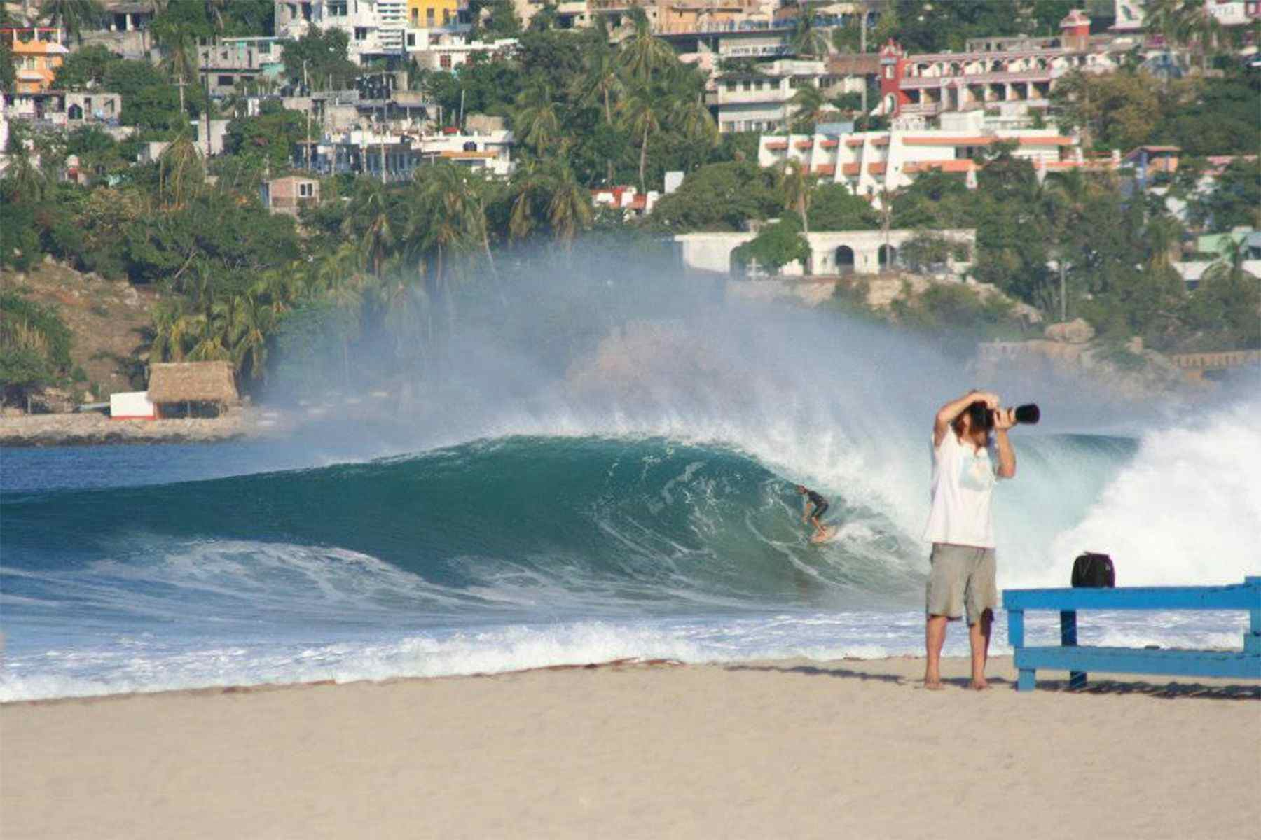 surfer in the barrel at puerto escondido, mexico, with a photographer on the beach in the foreground