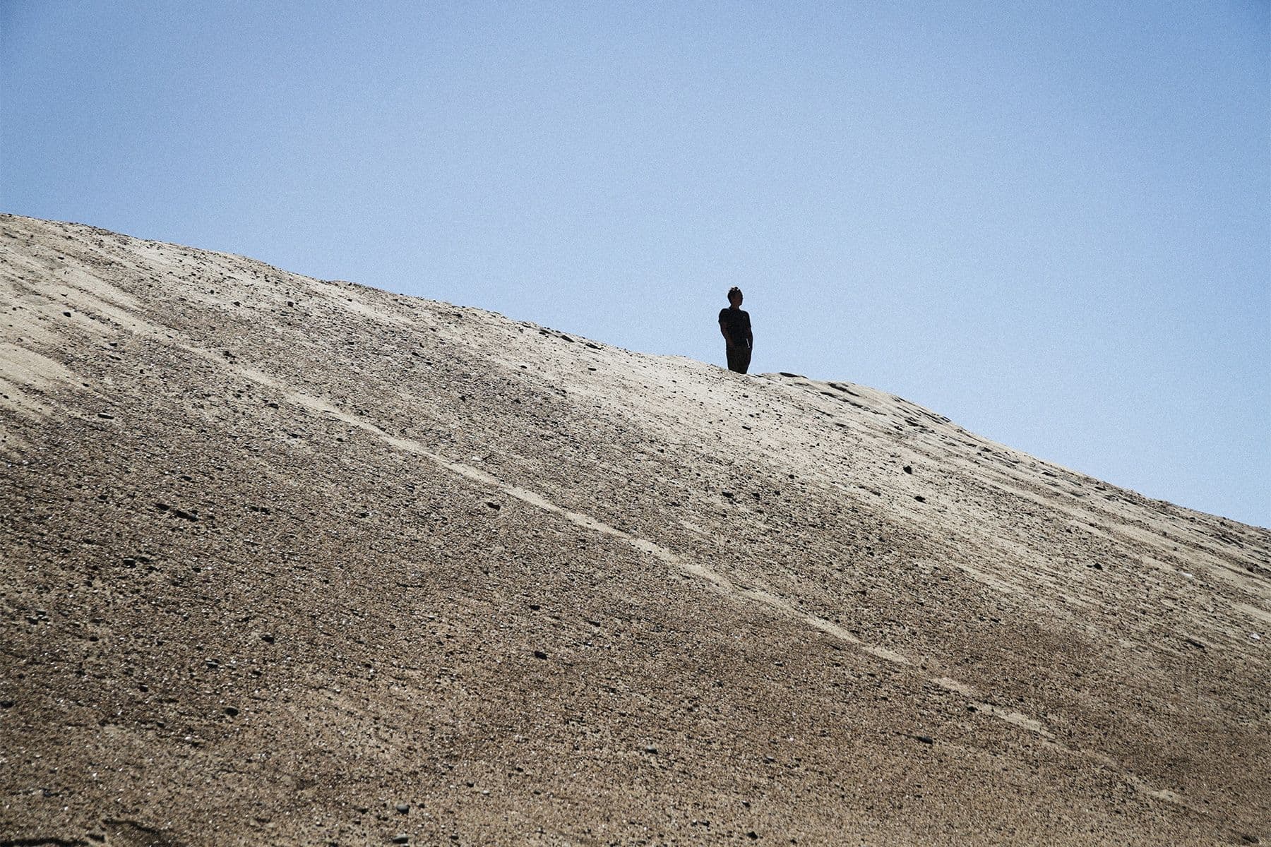 silhouette of a person stood on top of a sand dune