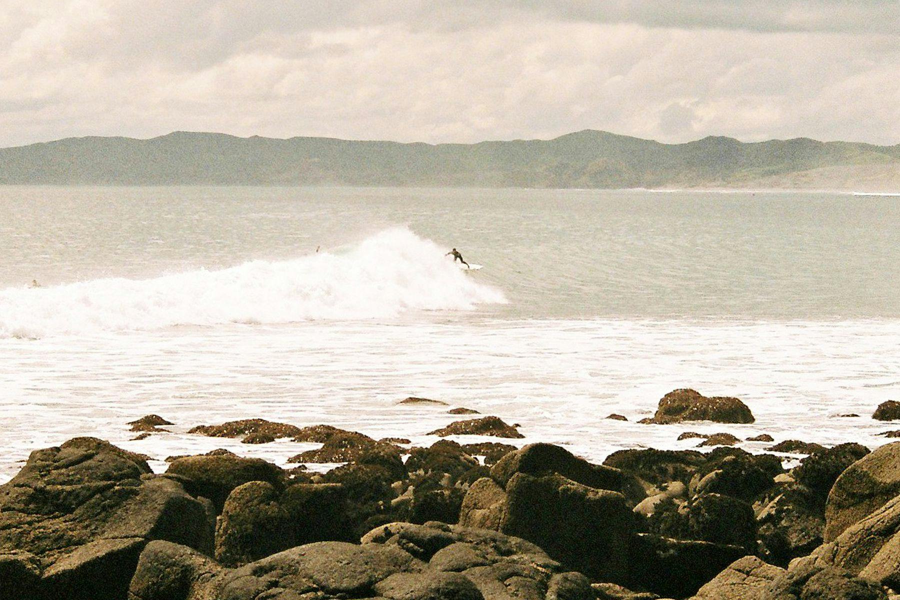 surfer riding down the line on a wave at raglan in new zealand