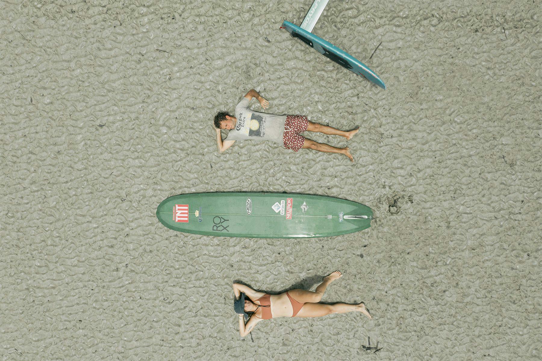 aerial drone photo of two surfers laying on their backs with their surfboards, by ana catarina