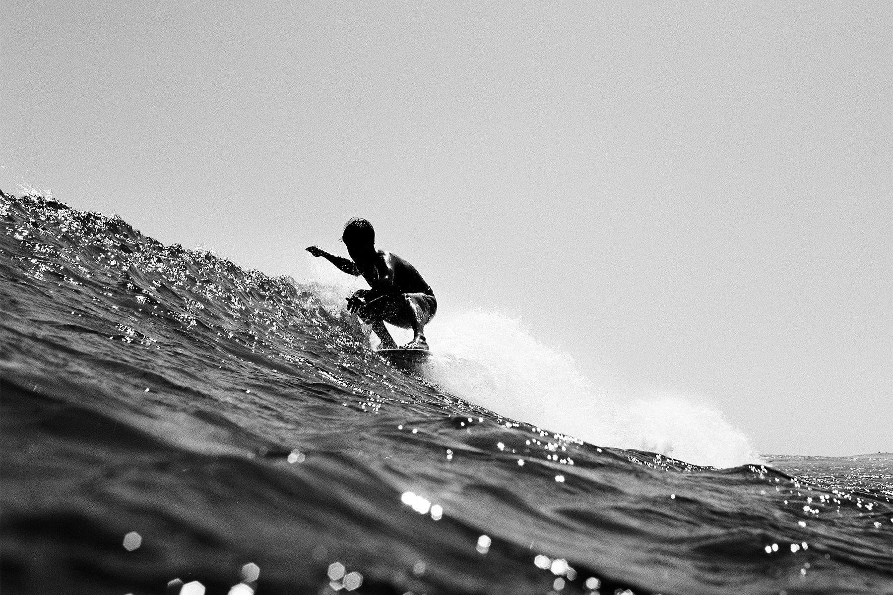 longboarder doing a stretch-five noseride at malibu, shot on black and white film by grant musso
