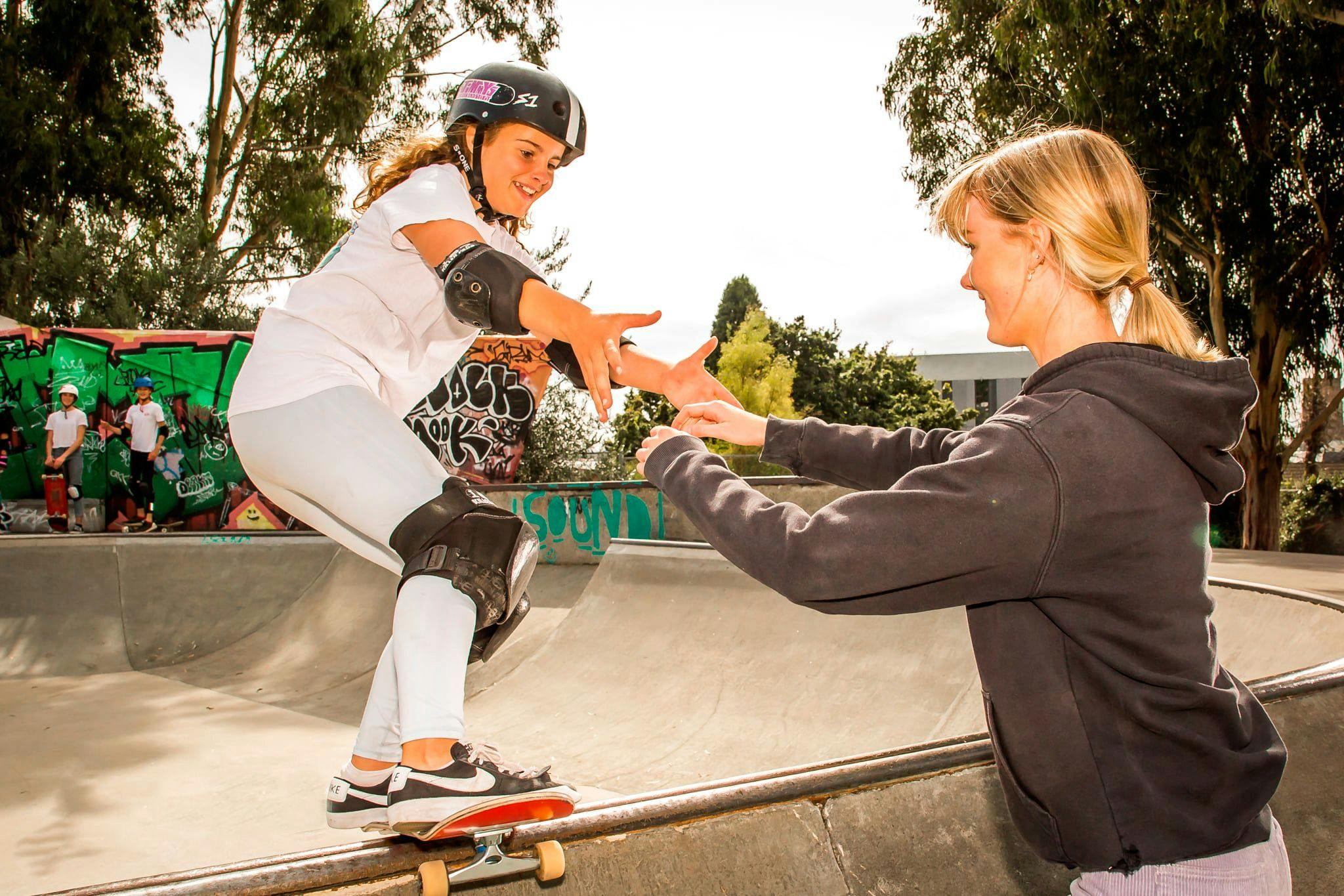 young girl learning to skaeboard at a skate park, photographed by liam mitchell
