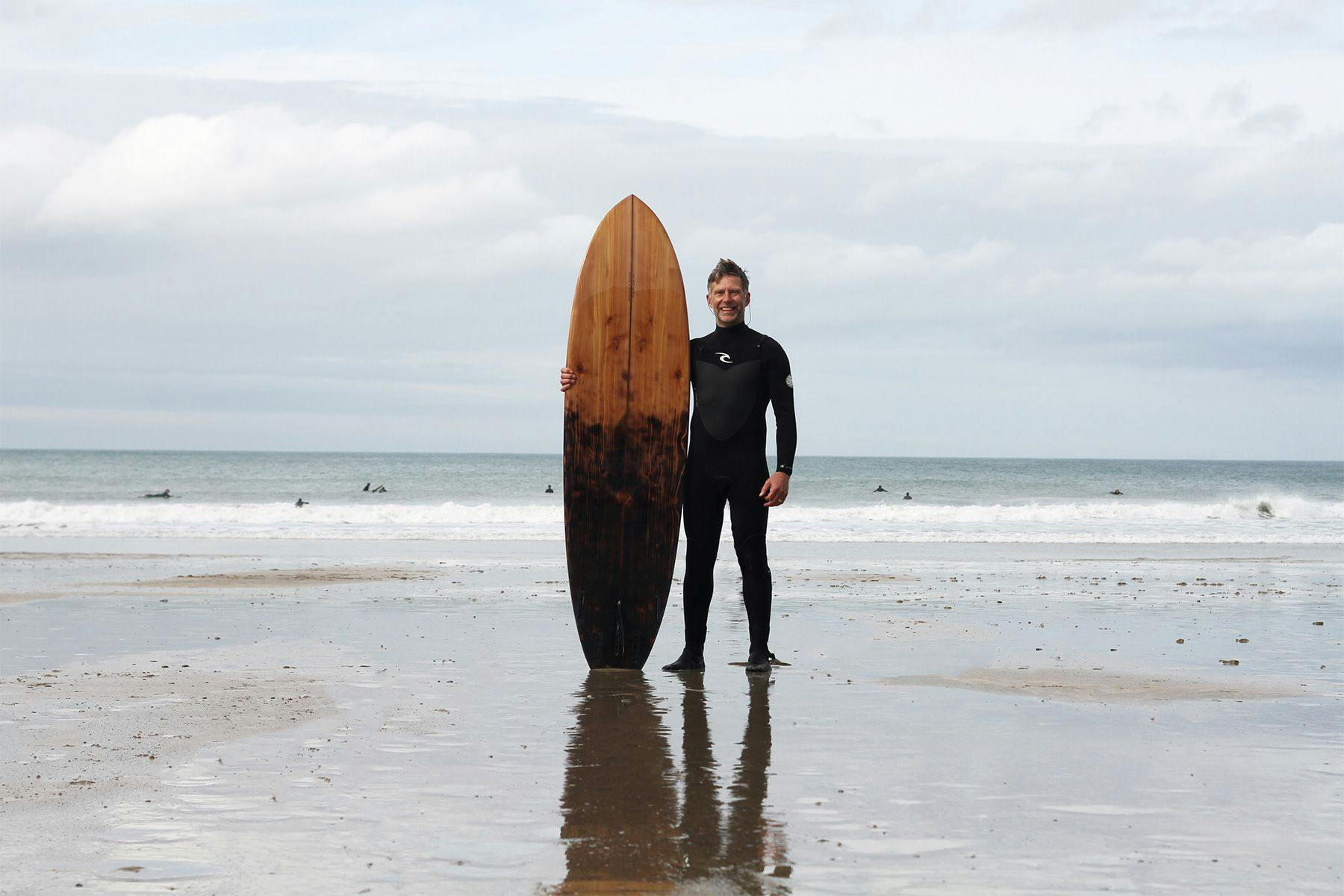 Ben with the shou sugi ban wooden surfboard that he made with Otter Surfboards