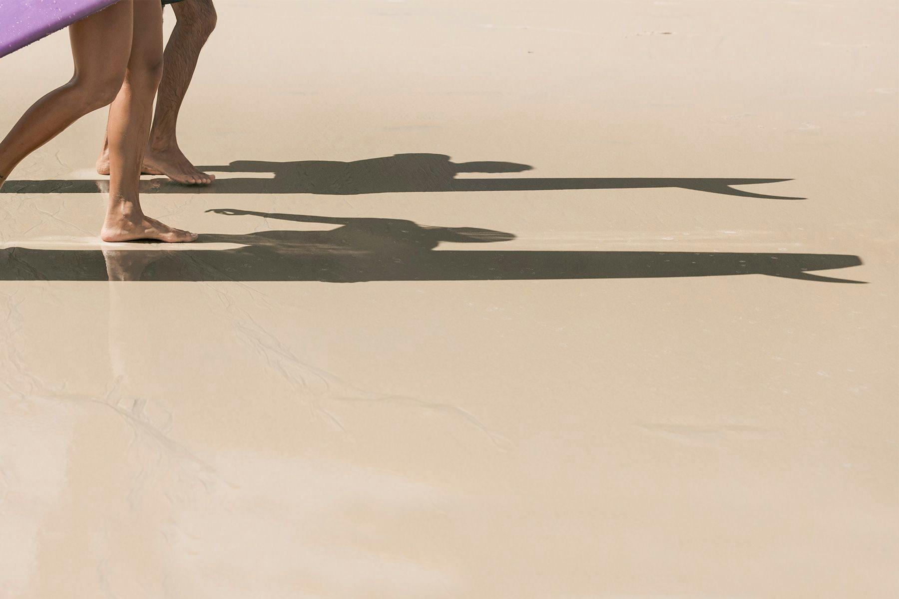 shadows of two surfers walking on the beach carrying their surfboards, by ana catarina