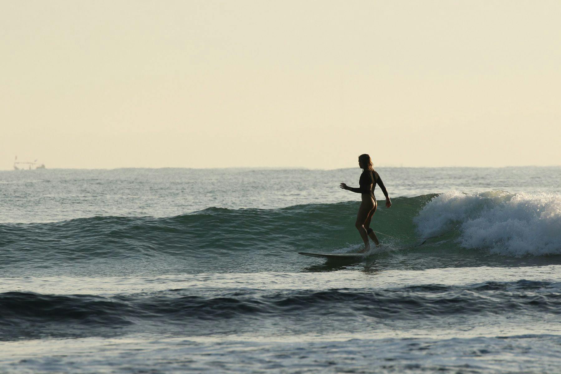 silhouetted woman surfing in indonesia