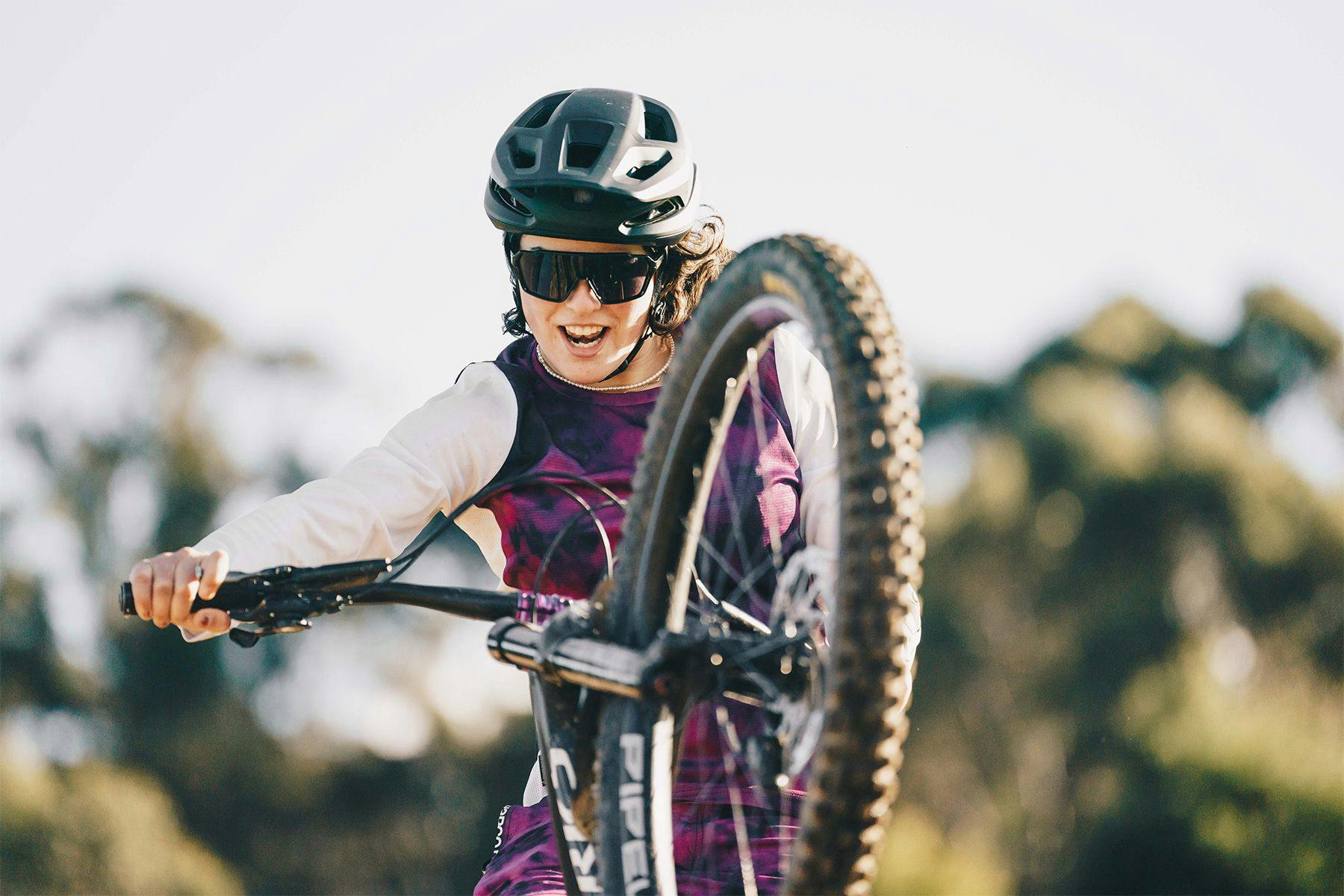 young woman pulling a wheelie on a mountain bike