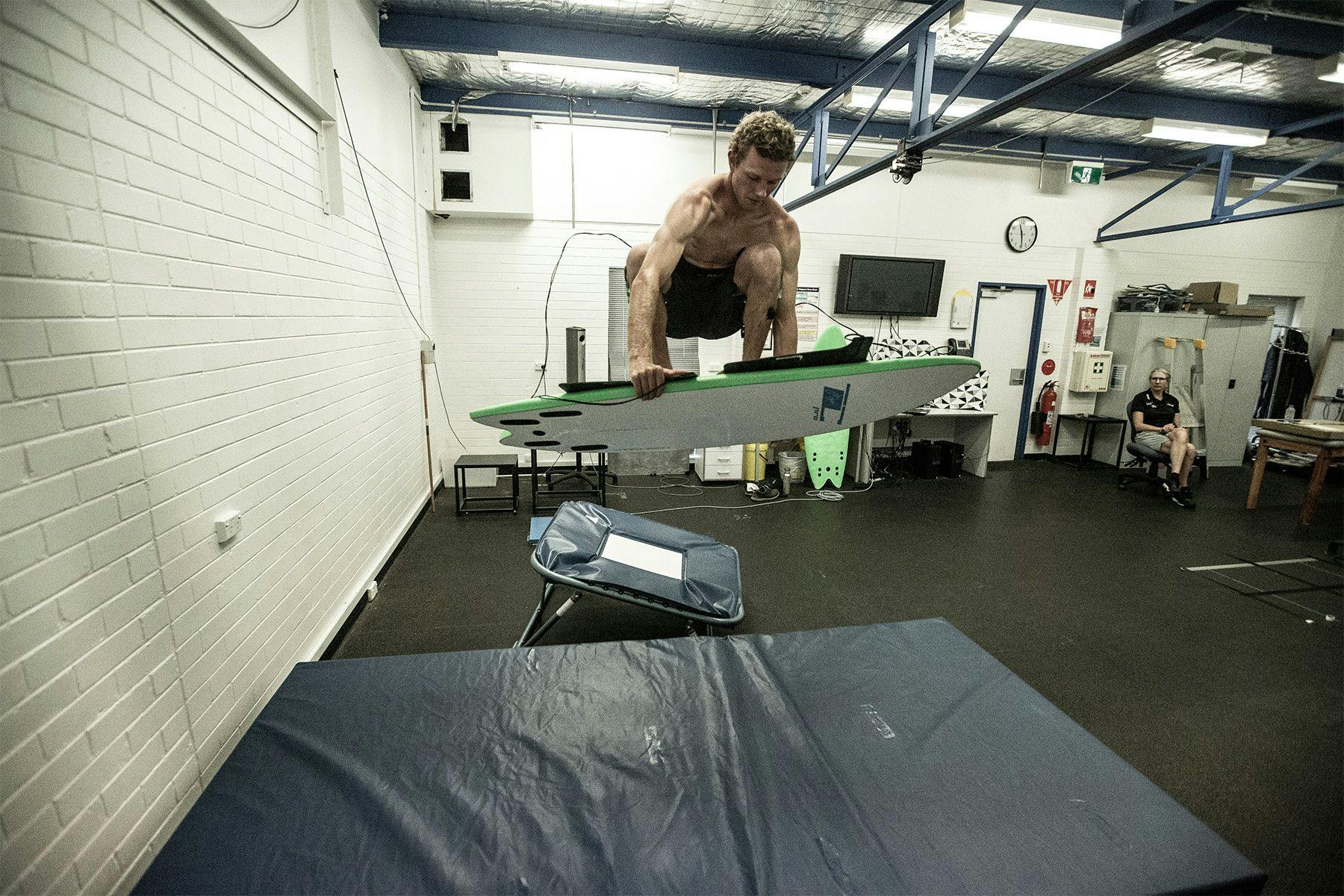 surfer in a sports science laboratory using a trampoline to replicate an aerial manoeuvre