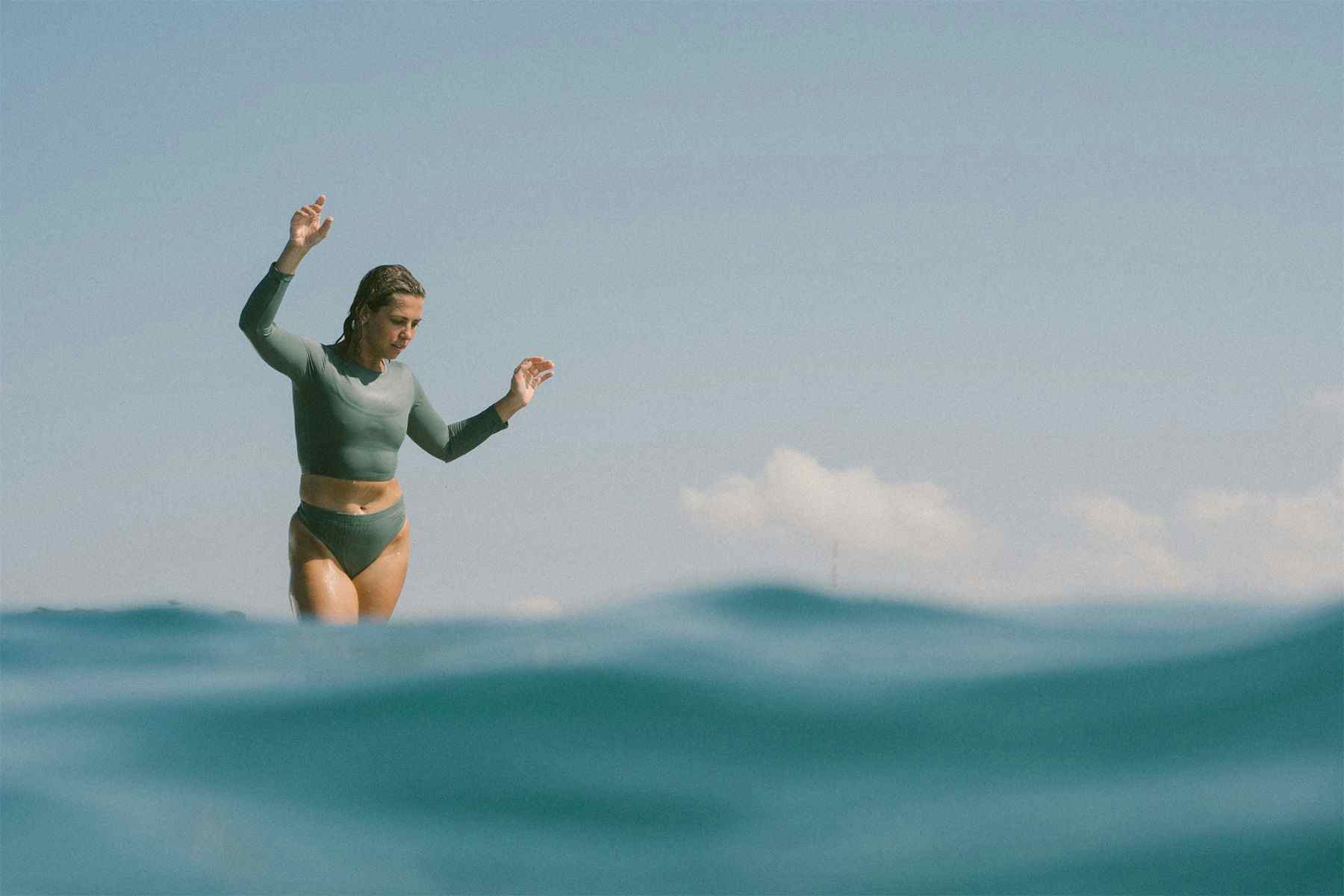 entrepreneur emma bukowski surfing a longboard as seen from behind the wave